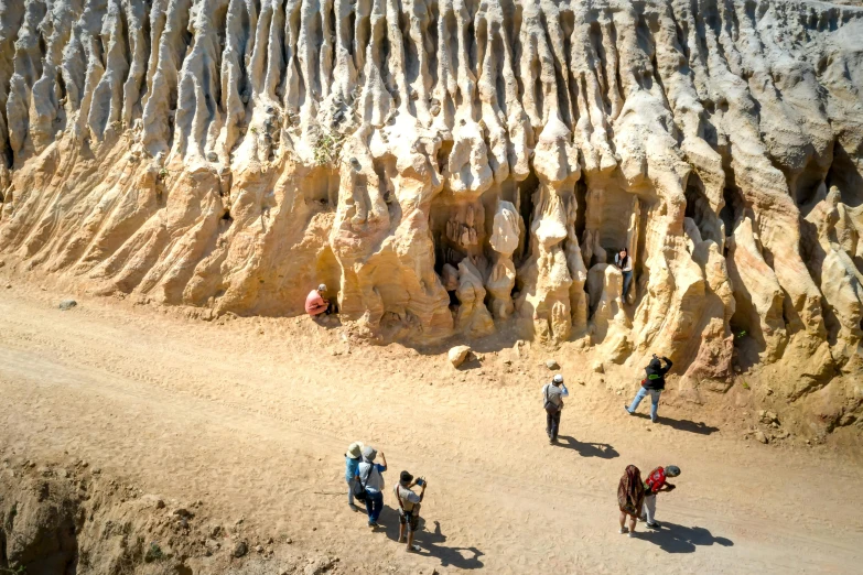 a group of people walk near a large carved out rock formation