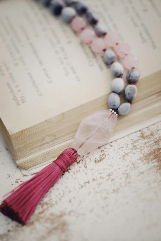 this beaded necklace with a tassel is resting on a book