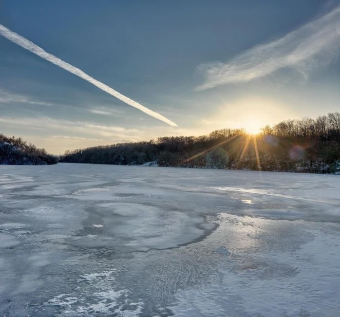 a sun is reflected in the water over the frozen river