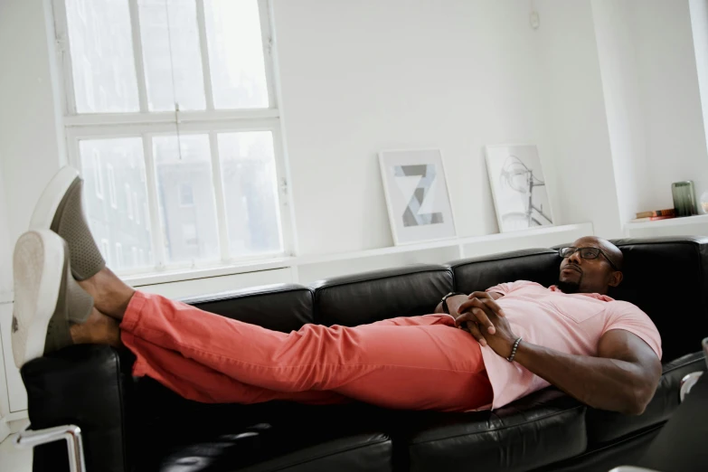 a man is resting on a couch wearing brown shoes