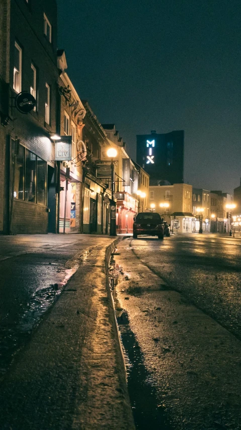 a dark city street with water running under buildings