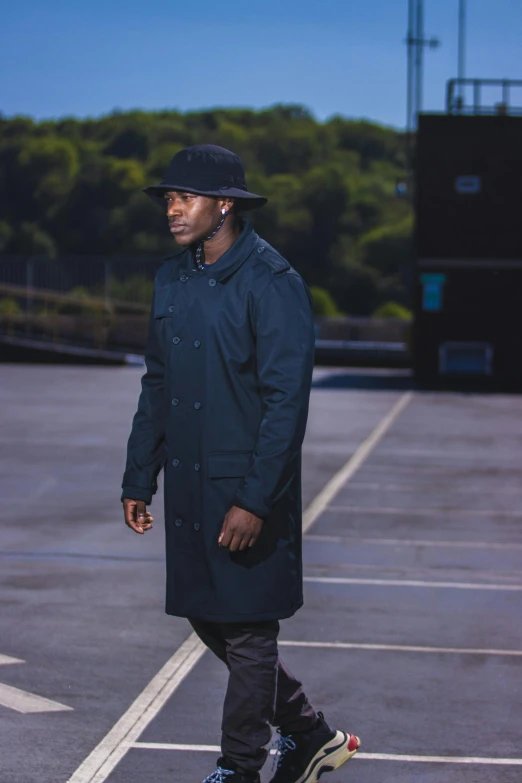 a black man in blue jacket standing on a skateboard