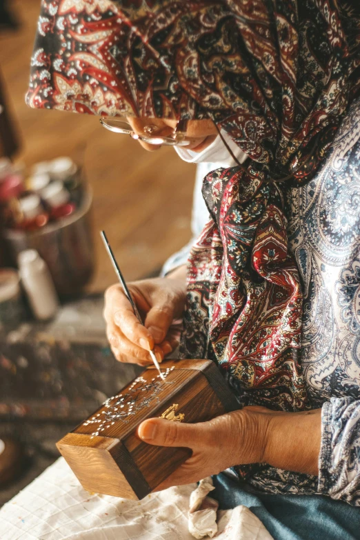 an individual is doing crafts on the wood and cloth