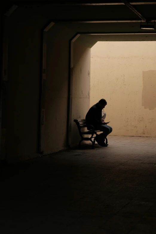 a man is sitting on a bench with the shadow