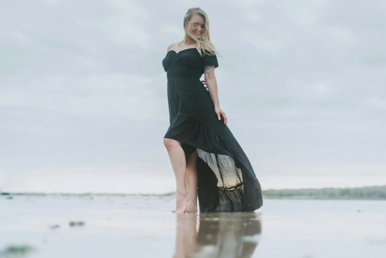 a woman in black standing on the beach