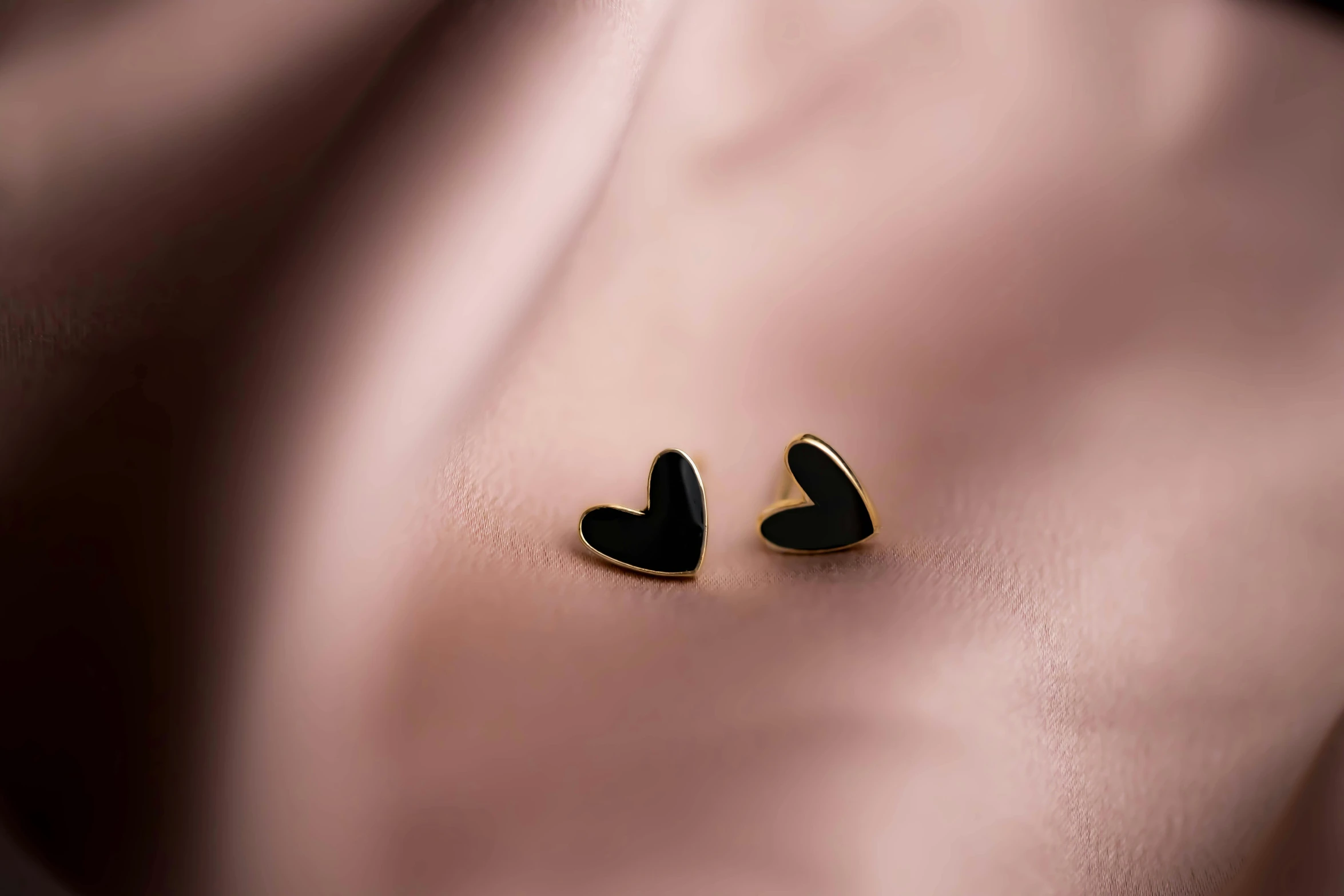 small heart shaped earrings against pink fabric