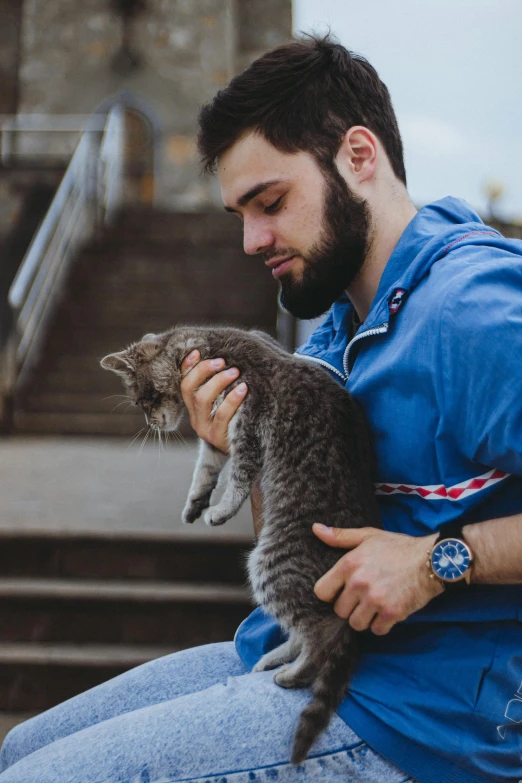 a man holds a striped cat outside of a church