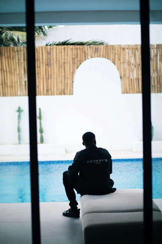 a man sitting on the edge of a swimming pool