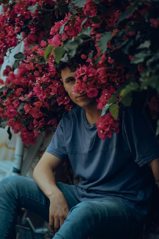 the young man is sitting in the shade of flowers