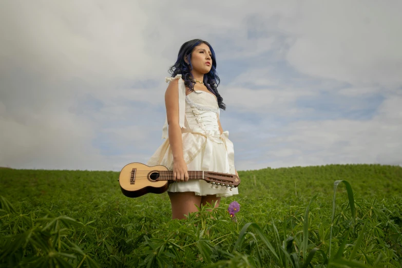 a  standing in a field holding a guitar