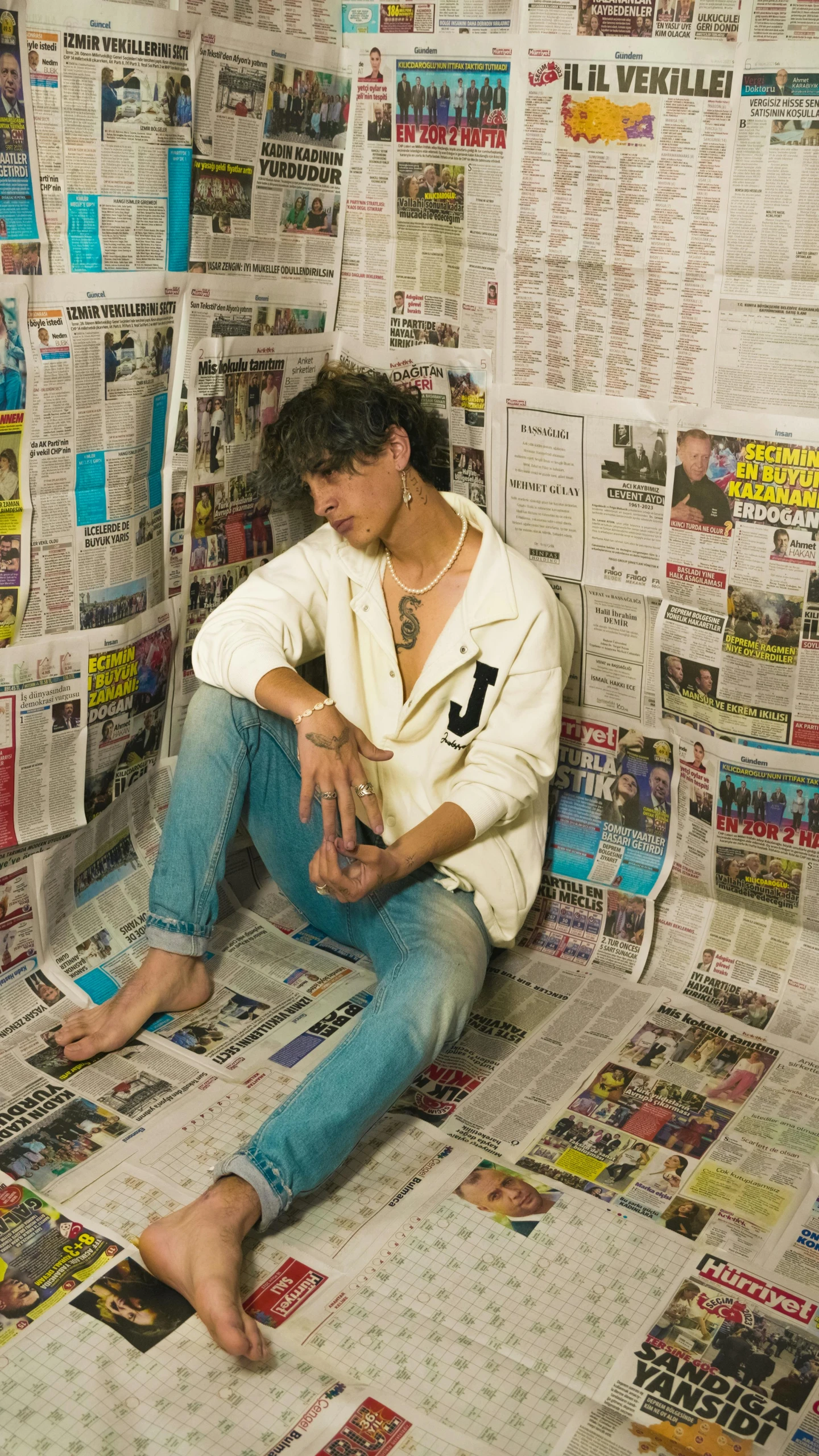 a young man seated on a newspaper page with his foot up