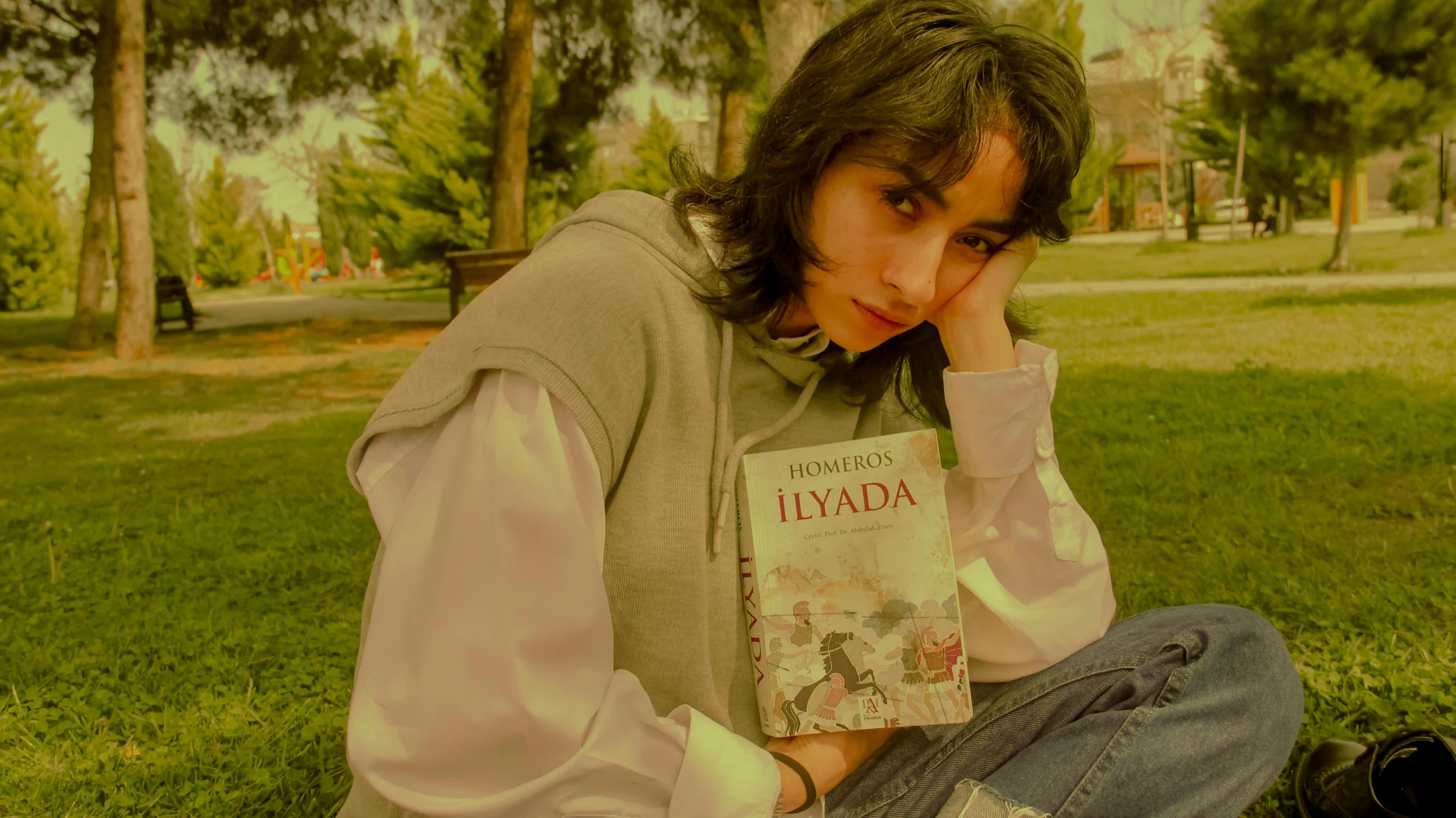 a person holding up a book in a grassy area