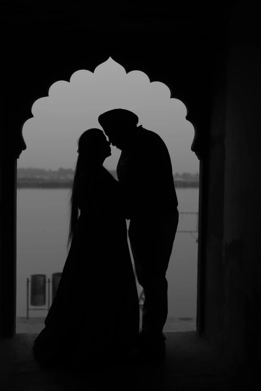 a bride and groom are standing together under an arch