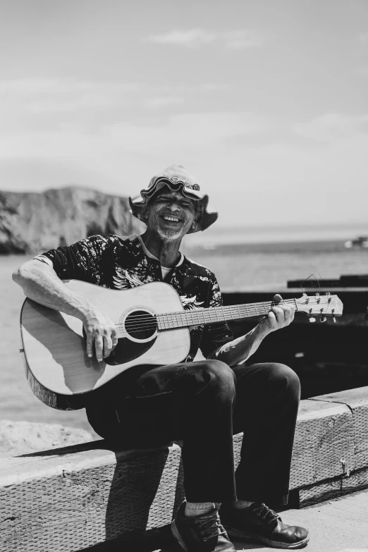 a man playing a guitar in front of the ocean