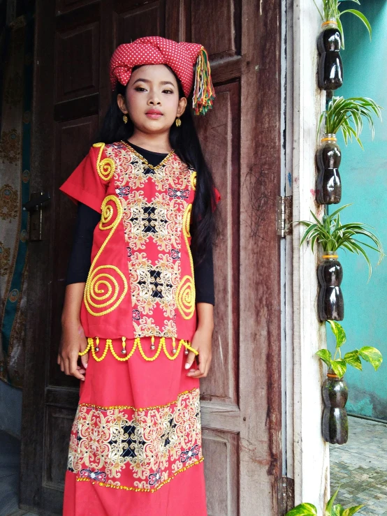 a  in an ethnic dress stands outside her doorway