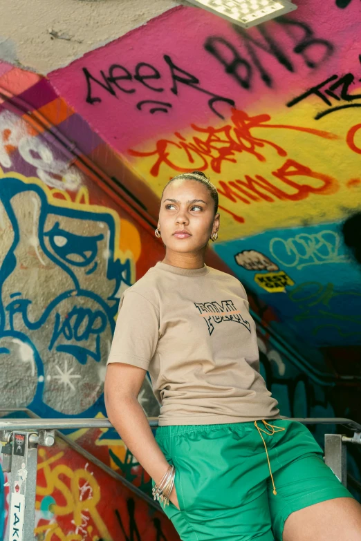 a girl in shorts and a shirt sitting against the wall