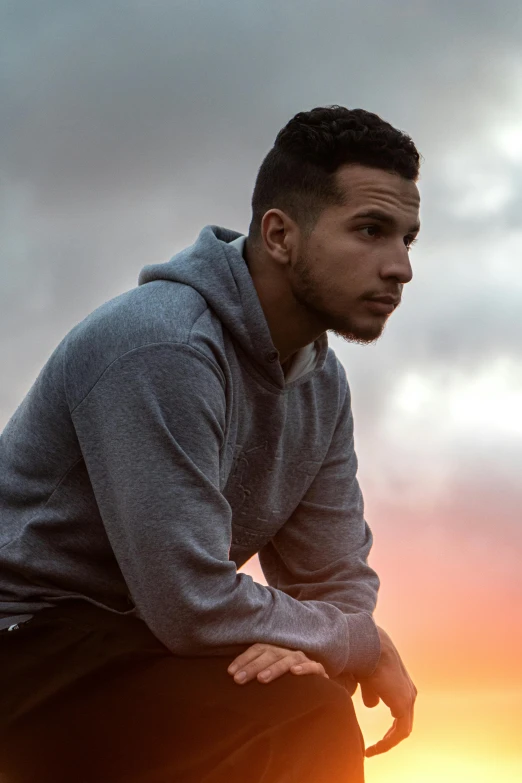 a man in grey sweatshirt and black pants leaning on the rail