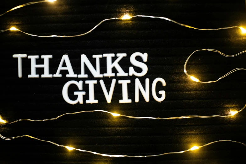 a message written on a black board with white lights and the words thanks giving