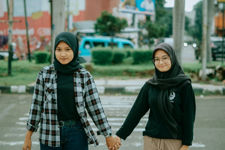 two girls are holding hands on the crosswalk