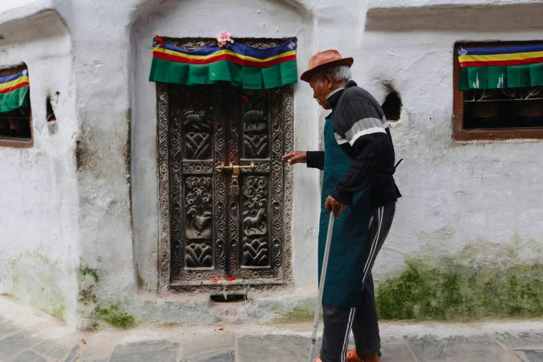 a man wearing a hat and standing in front of a doorway