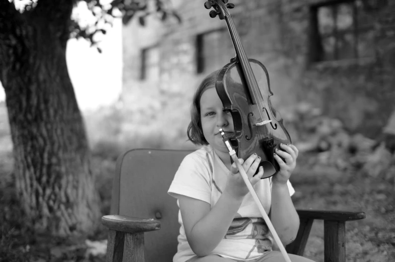 a little girl that is sitting down with a violin