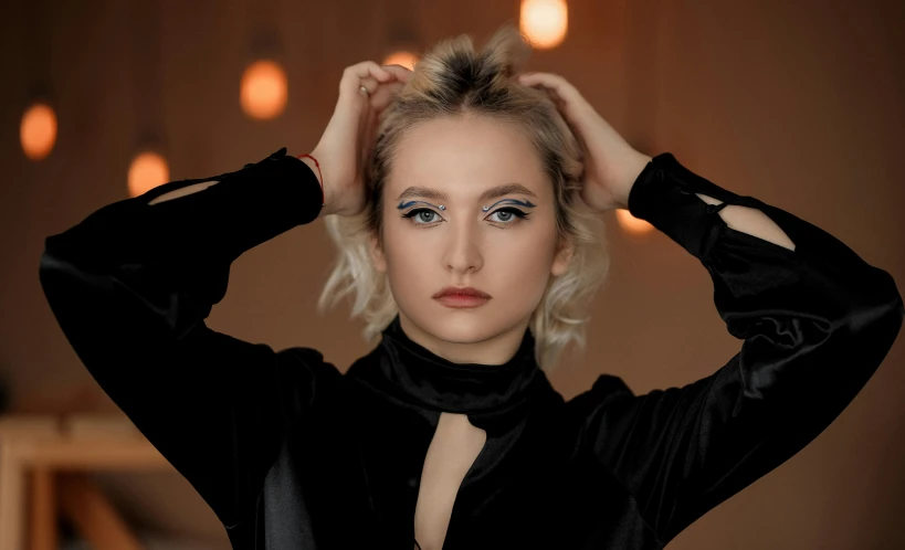 a woman poses in front of a wall with lights