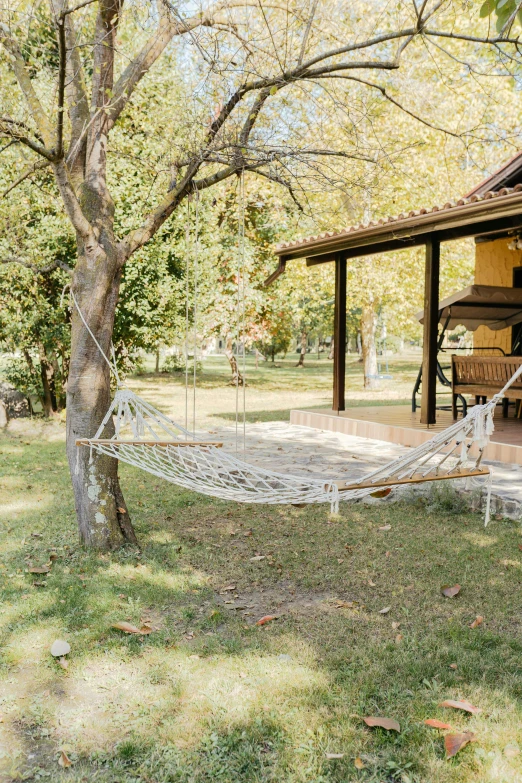 a hammock strung with a cotton rope on the back of a house