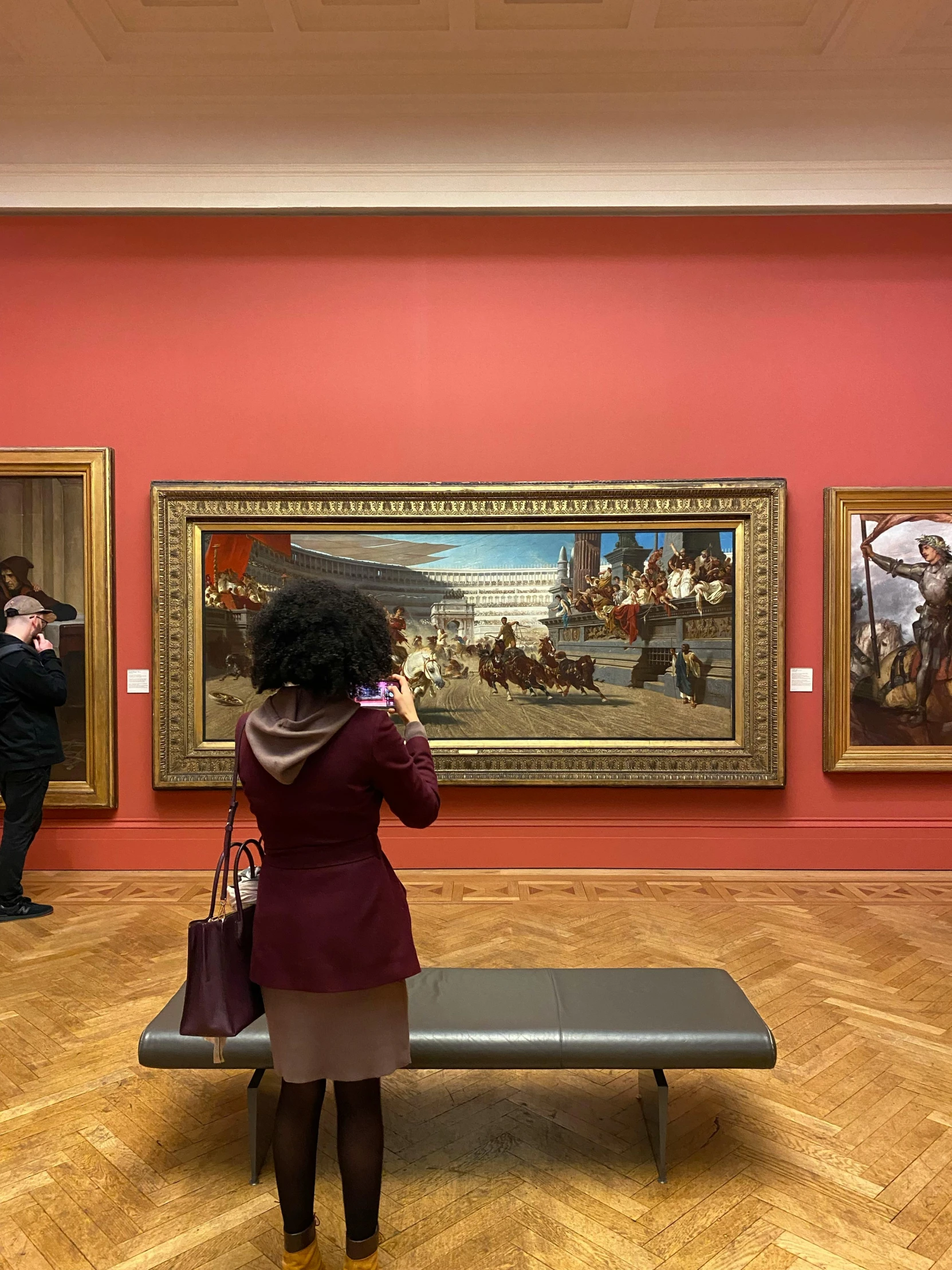 a woman is taking pictures in a museum with two paintings on the wall