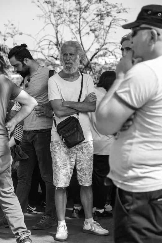 man standing on one leg in front of people with his hands crossed