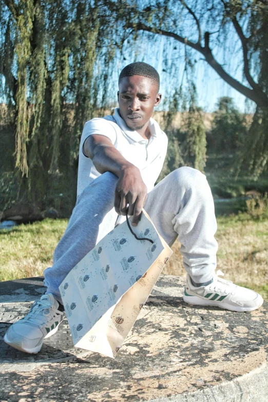 a young man in sweat pants and sneakers sitting on top of a cement slab