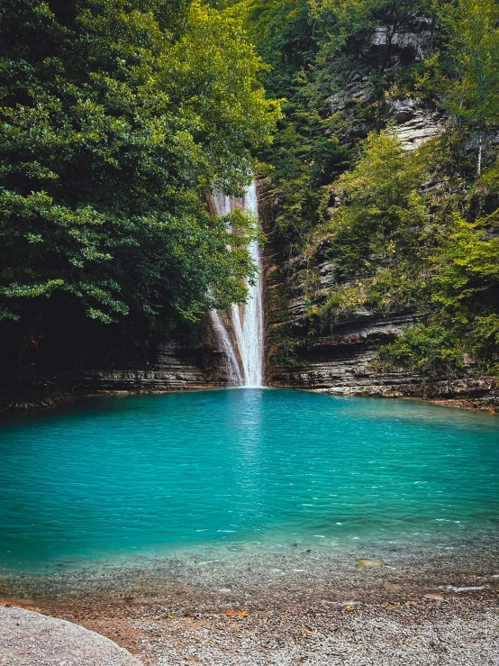 a waterfall in the woods near a lake