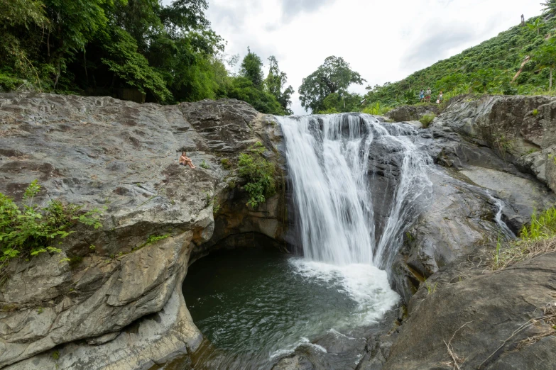 a waterfall with people diving from the cave