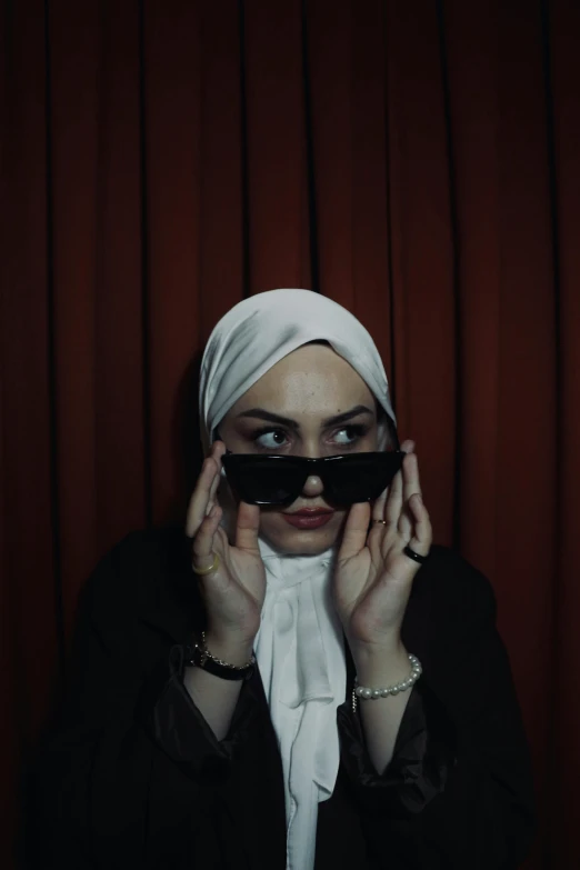 a woman in a turban covering her face with black shades