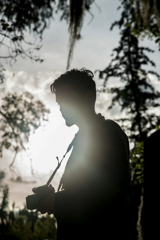 a person with a camera in their hand near a tree