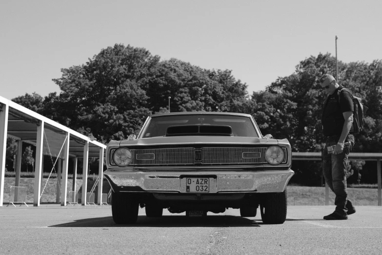 an old po of a man standing near an old car