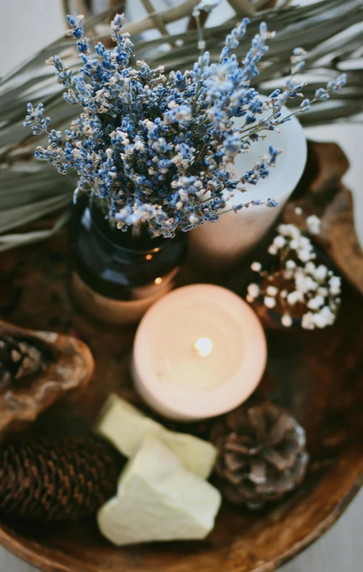 a small vase with some blue flowers sitting next to a candle