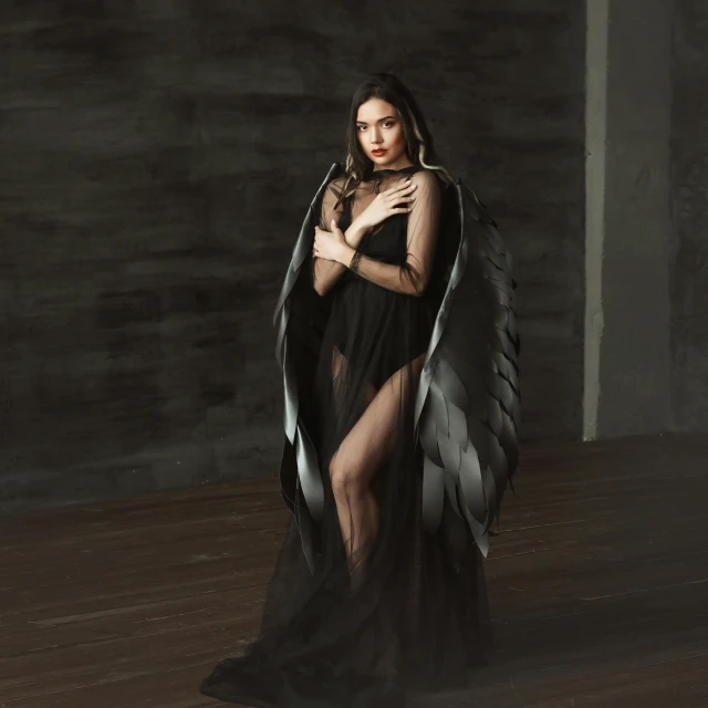 a model with dark hair wearing a black gown and large feathers