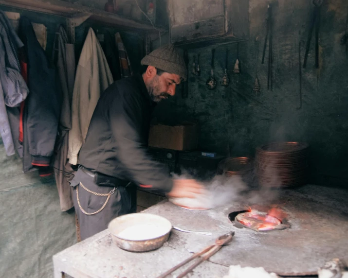a man cooking meat in an outdoor kitchen