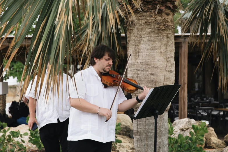 a man in white is playing a violin