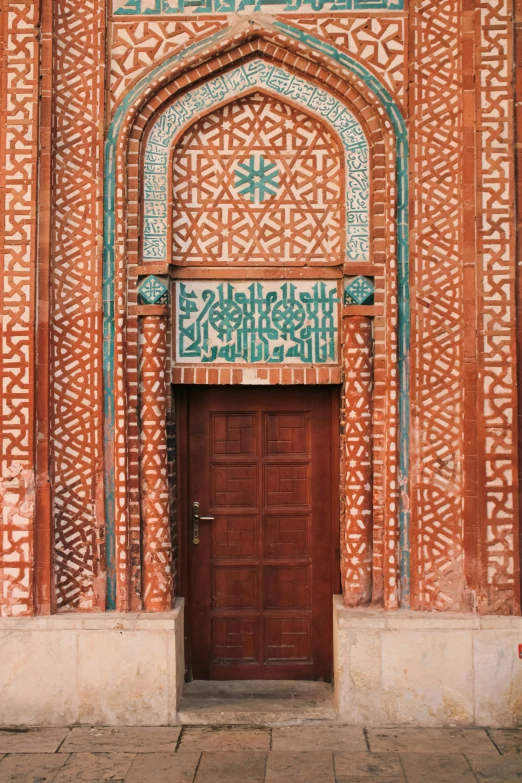 a wooden door in front of an ornate wall with tiles