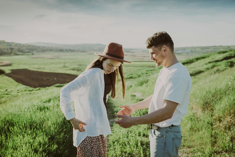 a couple dressed in white are standing in a field