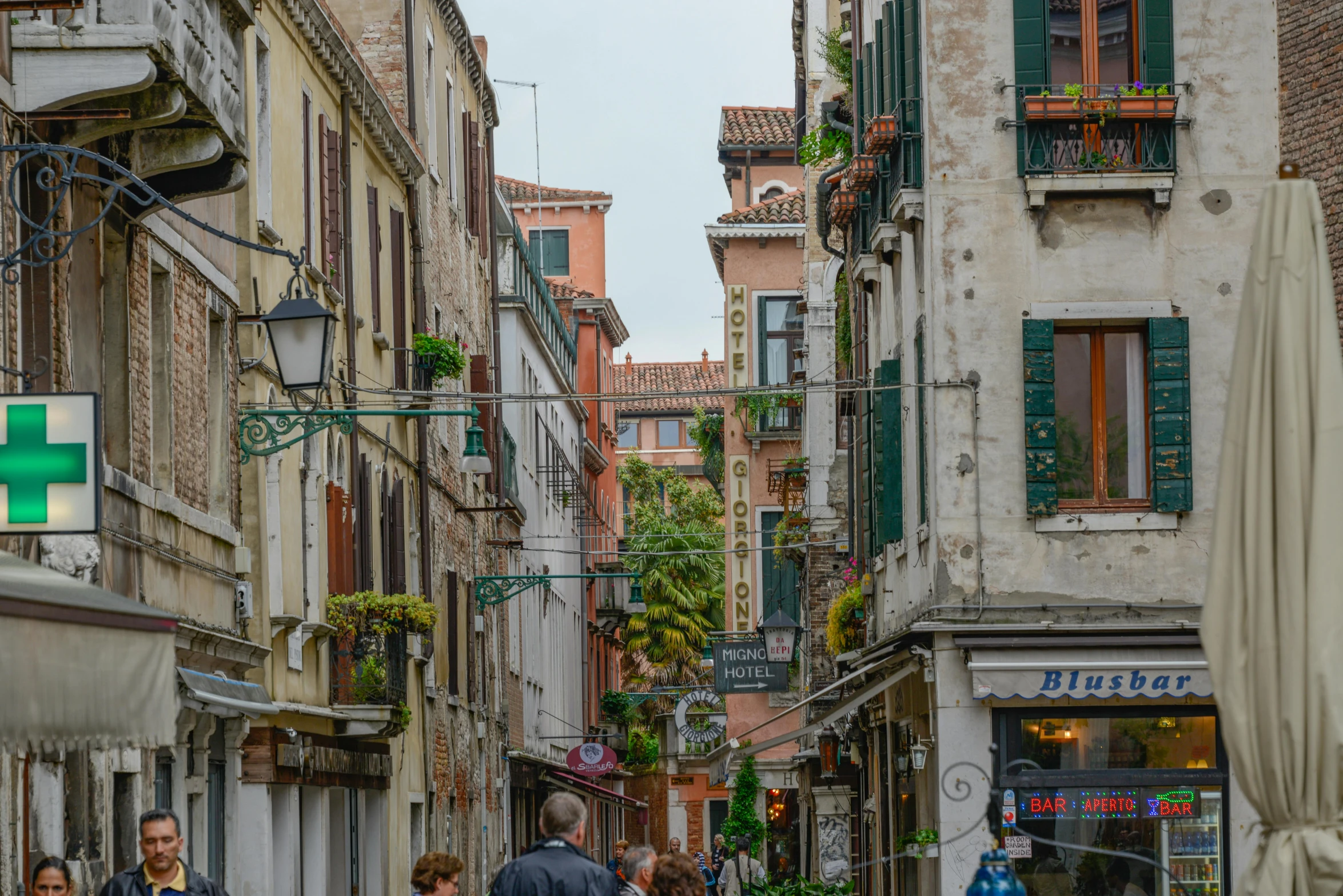 a narrow street with people walking down one and cars on the other