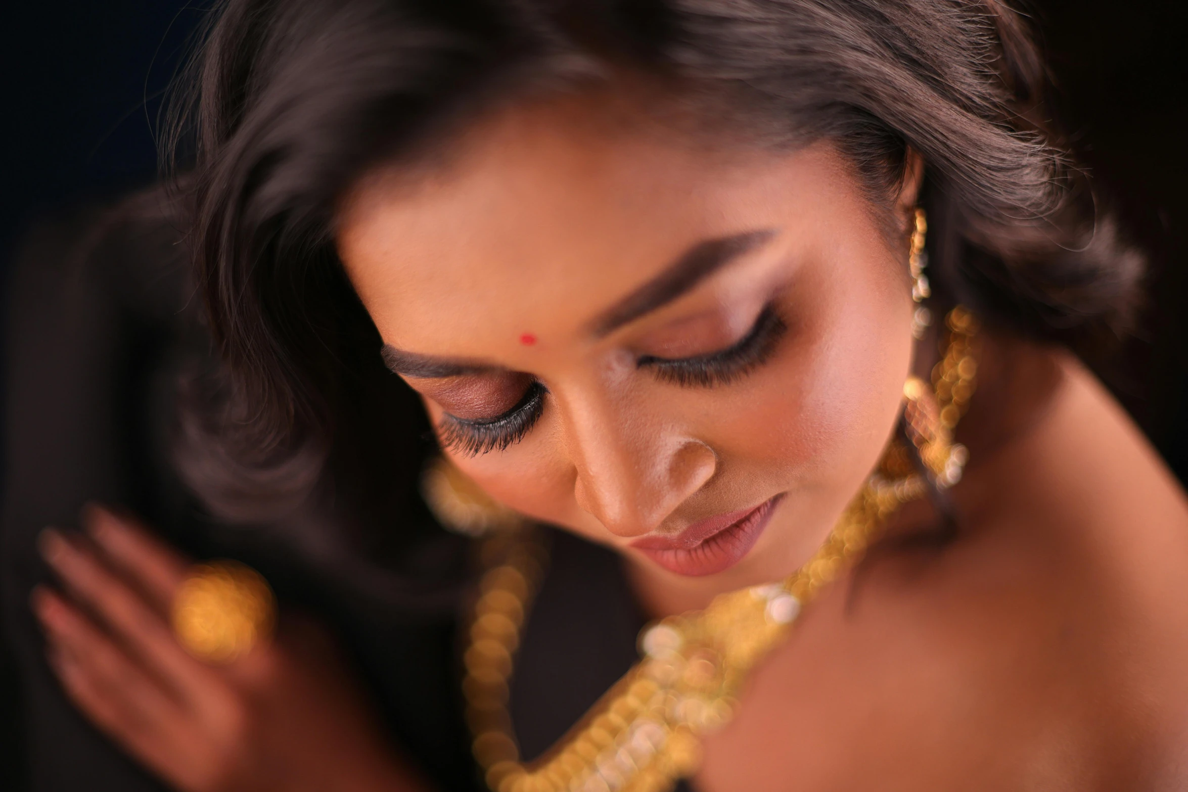 a woman wearing a necklace and earrings looks down