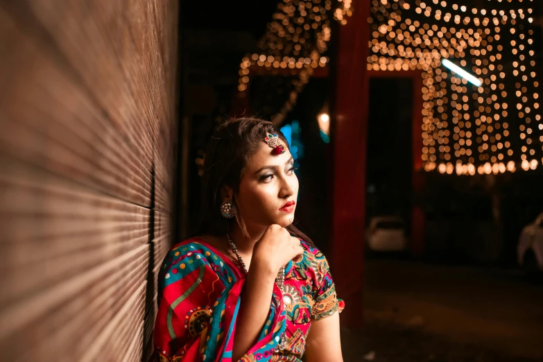 woman in a brightly colored sari leaning against a wall