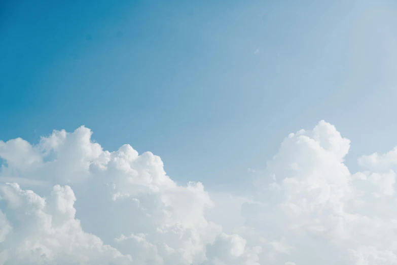 a plane flying over the blue cloudy sky