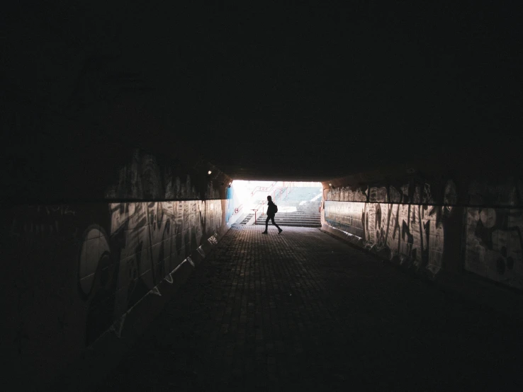 a person walking into a dark tunnel with the light on