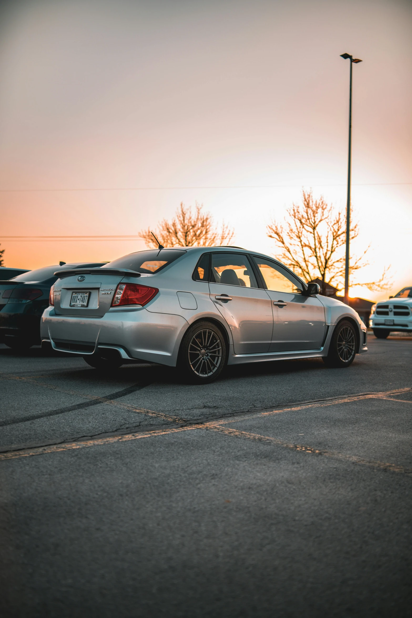 the rear of a silver car on a parking lot at sunset