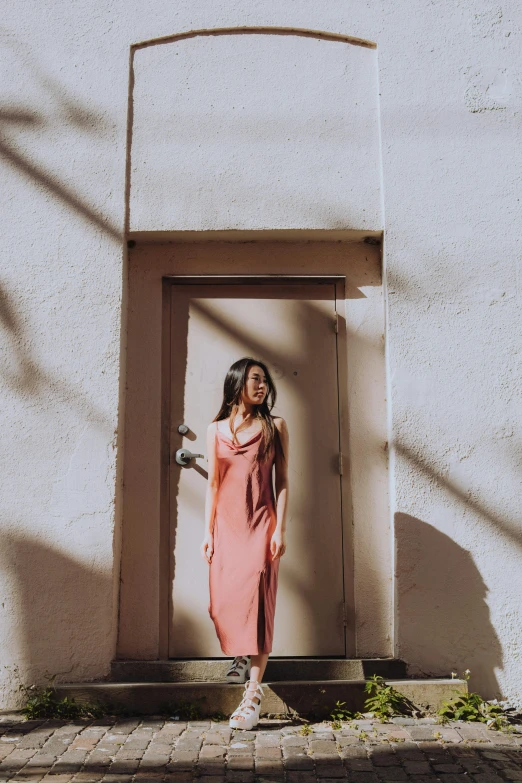 a woman stands in an open door on a sidewalk