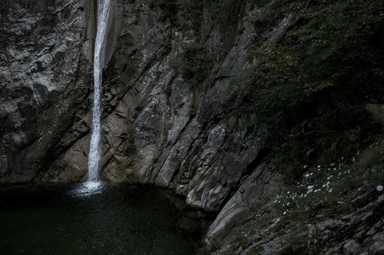 a waterfall running down into a body of water near a cliff