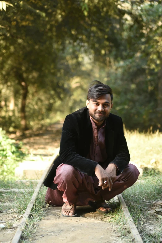 a man kneeling on some train tracks outside